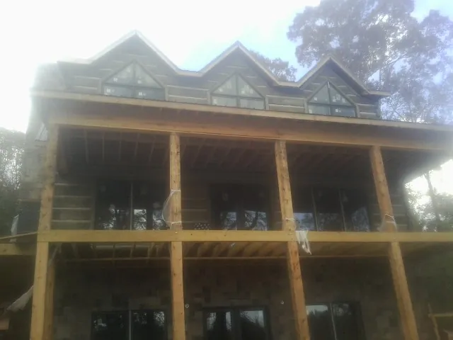 Dormers and porch framing on a large log home under construction — Roof Coating work by our crew in East Berne
