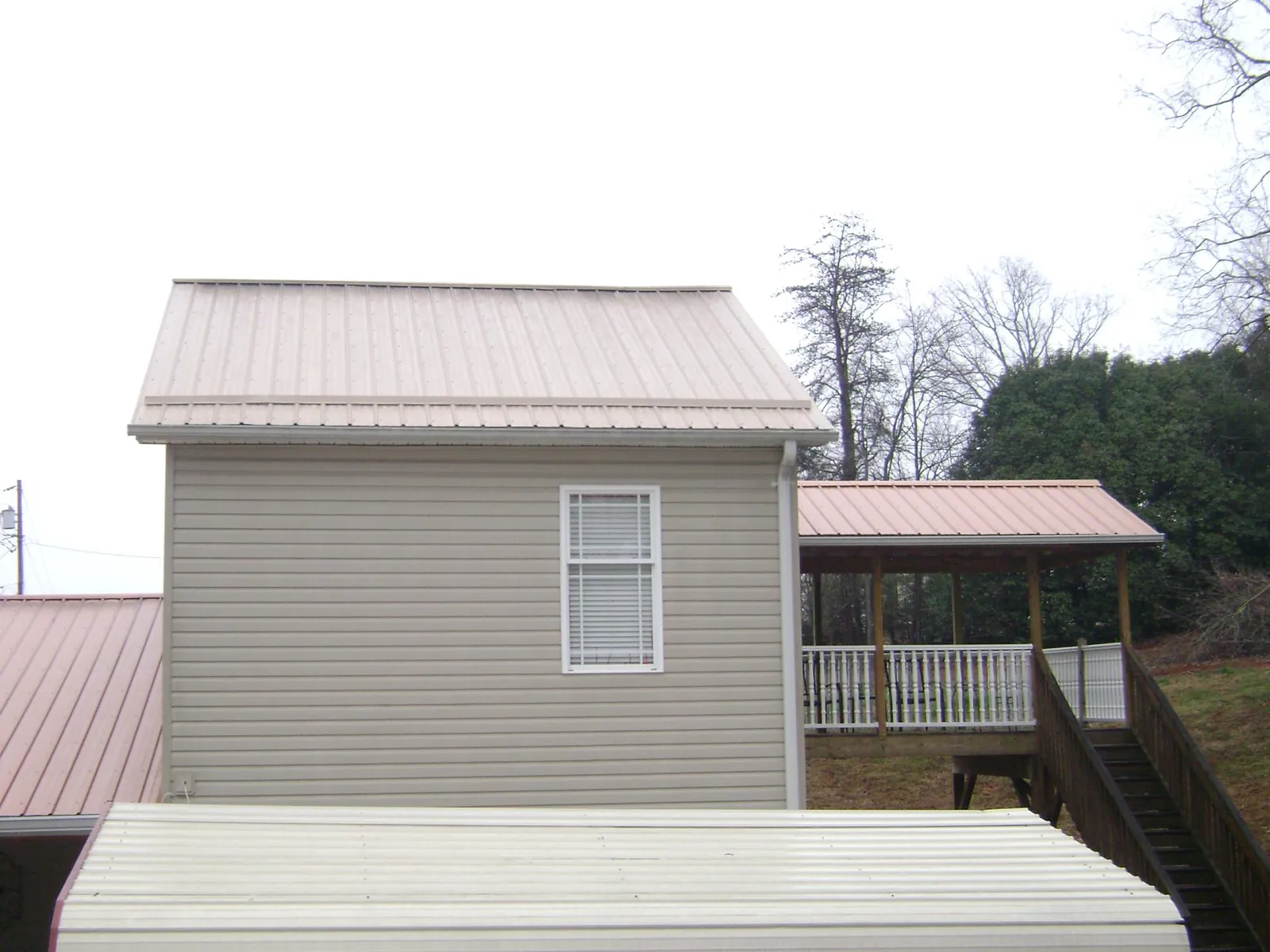 Tan metal roofs on a two story addition and attached porch, from a Roof Replacement job in East Berne