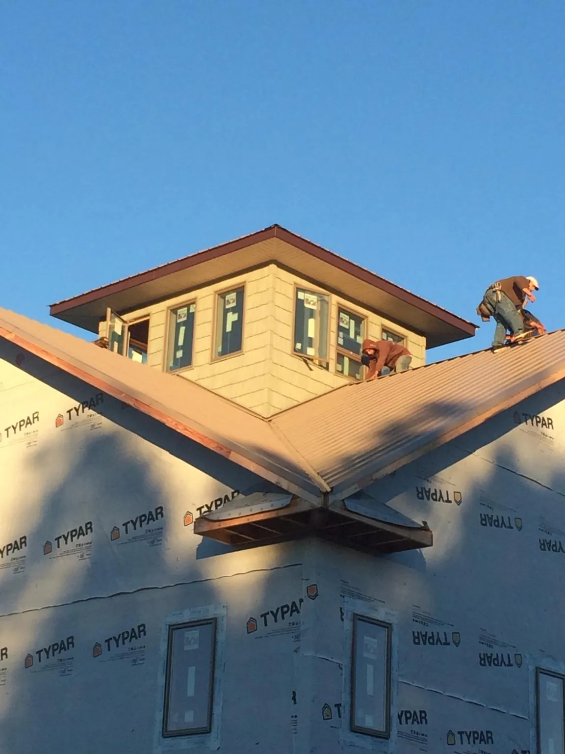Roofers working around a rooftop cupola on a new metal roof at sunset — Roof Waterproofing in East Berne by Roofing Brothers